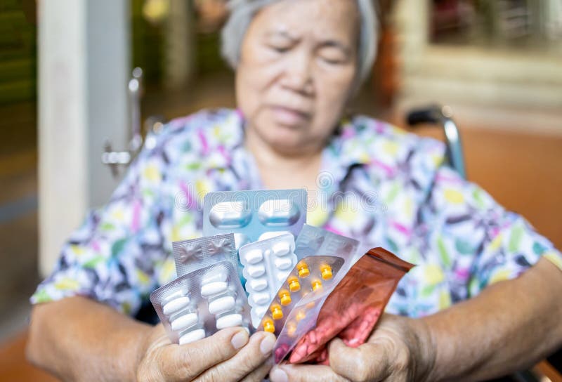 Mujer anciana enferma sosteniendo pastillas de medicina en silla de ruedas, triste mujer mayor mostrando muchos medicamentos, med foto de archivo libre de regalías Mujer anciana enferma sosteniendo pastillas de medicina en silla de ruedas, triste mujer mayor mostrando muchos medicamentos, med foto de archivo libre de regalías