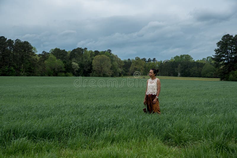 Mujer asi?tica en el campo rodeado por la hierba fotografía de archivo libre de regalías Mujer asi?tica en el campo rodeado por la hierba fotografía de archivo libre de regalías
