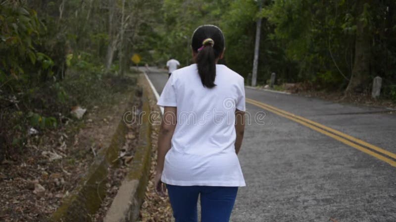 Mujer asiática caminando por la colina en la carretera Vista desde la parte trasera de las mujeres que apuntan a la montaña