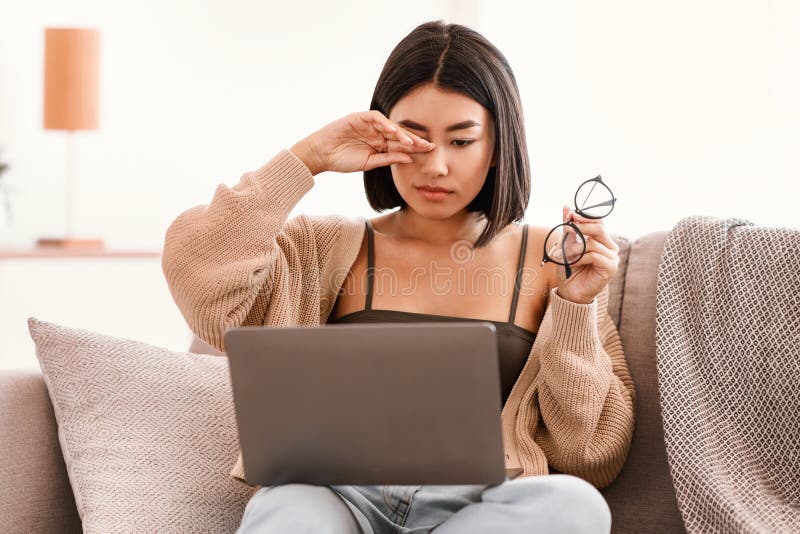 Mujer asiática cansada frotando el ojo usando una laptop imagen de archivo