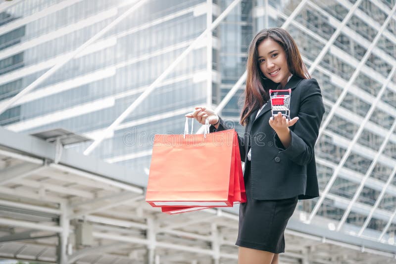 Mujer asiática de la belleza que sostiene el bolso y el carro de la compra de compras en alameda Shopaholic en viernes negro y co foto de archivo Mujer asiática de la belleza que sostiene el bolso y el carro de la compra de compras en alameda Shopaholic en viernes negro y co foto de archivo