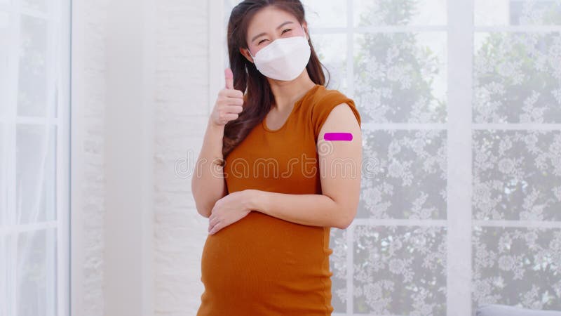 Mujer asiática embarazada que usa mascarilla facial recibió una vacuna anti virus alegre con vendaje embarazo de mujeres jóvenes q metrajes