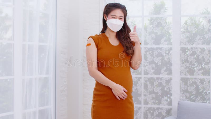 Mujer asiática embarazada que usa mascarilla facial recibió una vacuna anti virus alegre con vendaje embarazo de mujeres jóvenes q almacen de metraje de vídeo