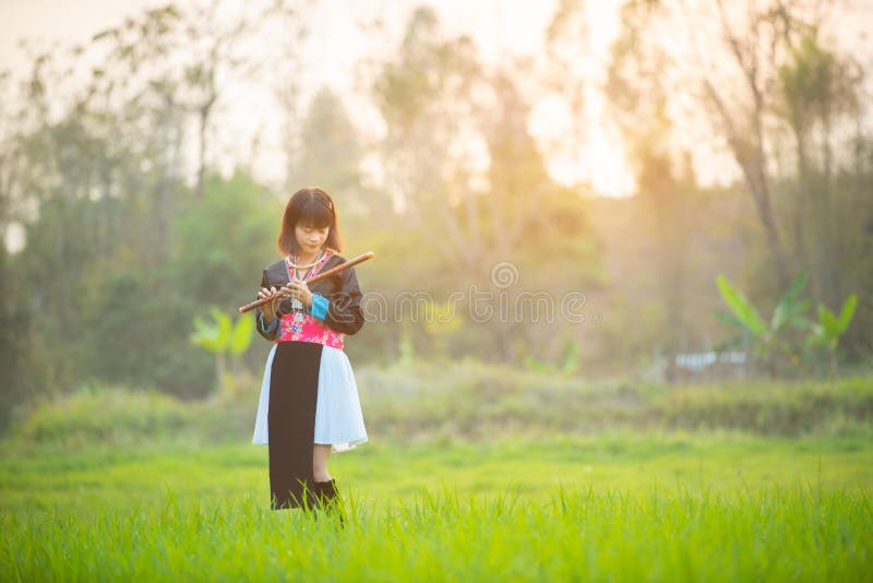 Mujer asiática en paseo de encargo del vestido de la tribu en el juego en la flauta con la cara romántica, proceso del campo de a imágenes de archivo libres de regalías Mujer asiática en paseo de encargo del vestido de la tribu en el juego en la flauta con la cara romántica, proceso del campo de a imágenes de archivo libres de regalías