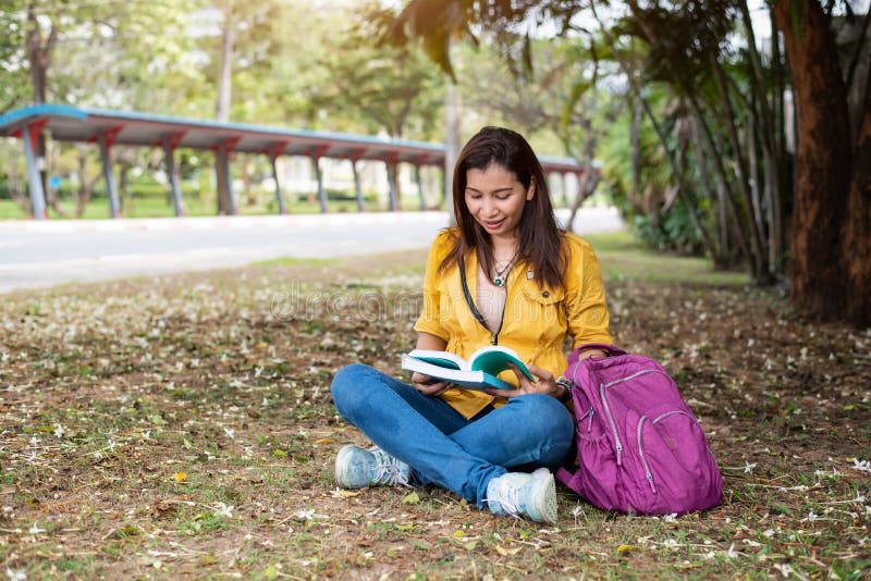 Mujer asiática feliz que se sienta y libros de lectura en el parque u de la universidad imagen de archivo libre de regalías Mujer asiática feliz que se sienta y libros de lectura en el parque u de la universidad imagen de archivo libre de regalías