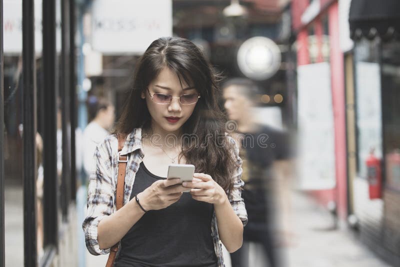 Mujer asiática hermosa que camina en la calle urbana y que conecta encendido imagenes de archivo Mujer asiática hermosa que camina en la calle urbana y que conecta encendido imagenes de archivo