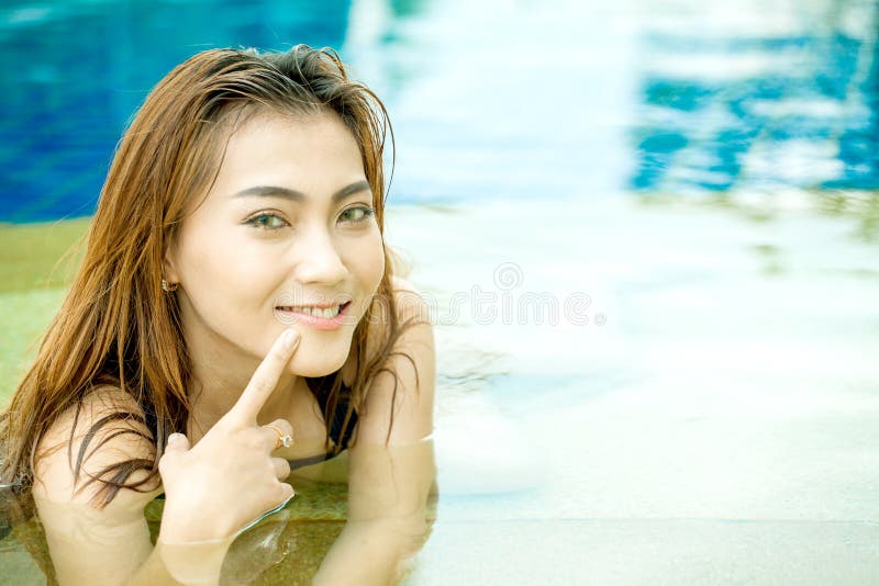 Mujer asiática joven hermosa que sonríe en un finger po de la piscina imágenes de archivo libres de regalías Mujer asiática joven hermosa que sonríe en un finger po de la piscina imágenes de archivo libres de regalías