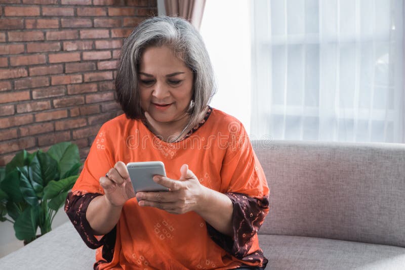 Mujer asiática mayor que usa su teléfono elegante fotografía de archivo Mujer asiática mayor que usa su teléfono elegante fotografía de archivo