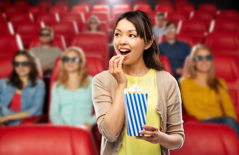 Mujer asiática que come las palomitas en el cine fotos de archivo libres de regalías Mujer asiática que come las palomitas en el cine fotos de archivo libres de regalías