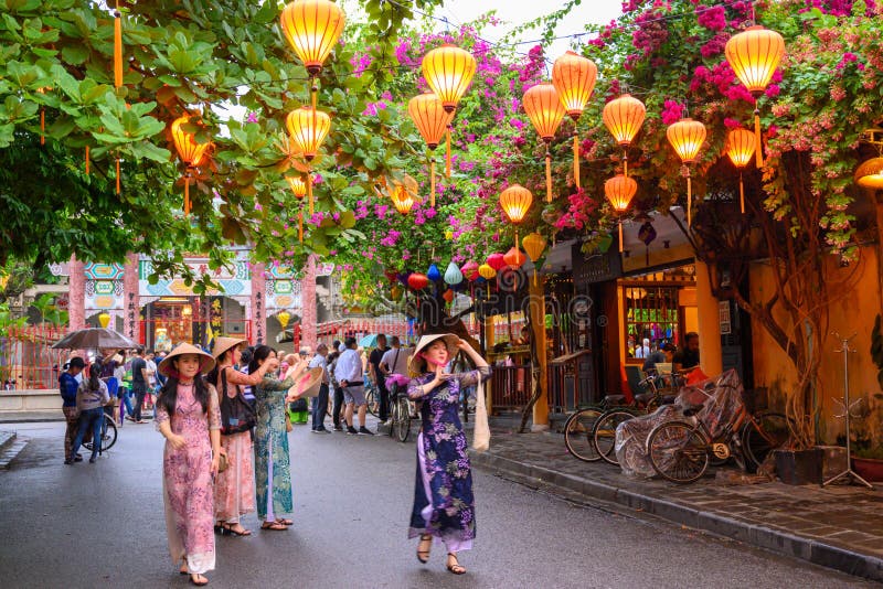 Mujer asiática que da un paseo a través del callejón con lampions en el destino turístico Hoi An, Vietnam