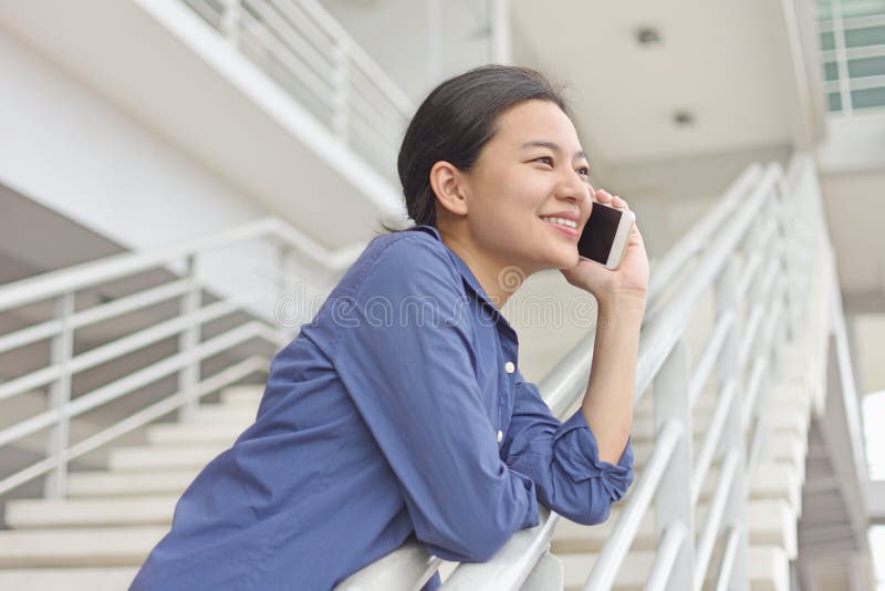 Mujer asiática que disfruta de la conversación telefónica con el amigo imagenes de archivo
