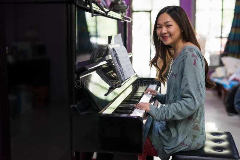 Mujer asiática que juega el piano en casa fotos de archivo Mujer asiática que juega el piano en casa fotos de archivo