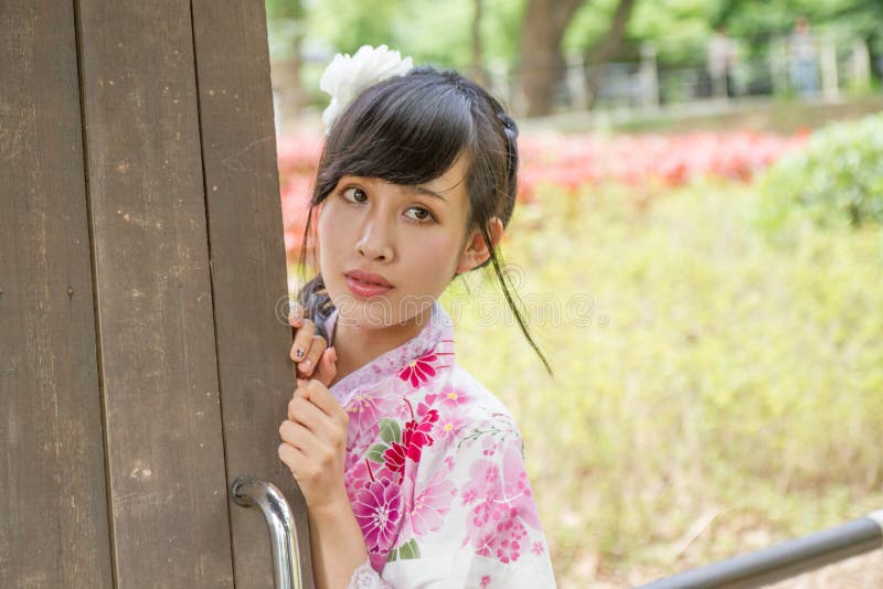 Mujer asiática que lleva un kimono al lado de puerta vieja foto de archivo Mujer asiática que lleva un kimono al lado de puerta vieja foto de archivo