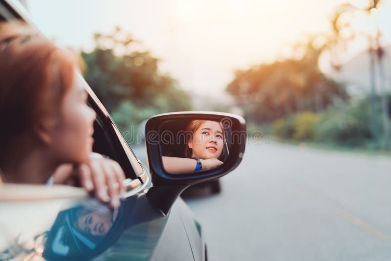 Mujer asiática que sonríe con el viaje en coche de la ventana trasera que conduce vacaciones de verano del viaje por carretera foto de archivo Mujer asiática que sonríe con el viaje en coche de la ventana trasera que conduce vacaciones de verano del viaje por carretera foto de archivo