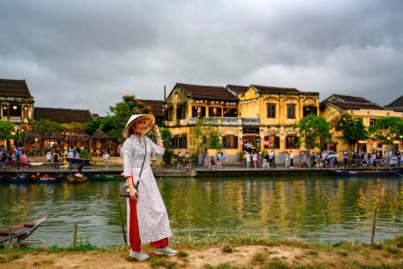 Mujer asiática que toma las fotos en el canal en el destino turístico Hoi An, mujeres vietnamitas en Hoi An, Vietnam foto de archivo libre de regalías Mujer asiática que toma las fotos en el canal en el destino turístico Hoi An, mujeres vietnamitas en Hoi An, Vietnam foto de archivo libre de regalías