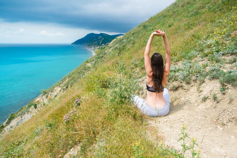 Mujer atlética irreconocible 25-30 que se sienta en la colina en sujetador y pantalones Hacer yoga foto de archivo libre de regalías Mujer atlética irreconocible 25-30 que se sienta en la colina en sujetador y pantalones Hacer yoga foto de archivo libre de regalías