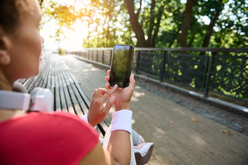 Mujer atlética que sostiene un smartphone con pantalla negra en blanco y muestra espacio para copiar para el diseño de aplicacione fotos de archivo