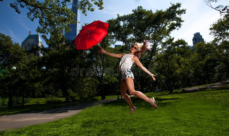Young Blonde Athletic woman holding a Red Umbrella in Central Park. Young Blonde Athletic woman holding a Red Umbrella in Central Park