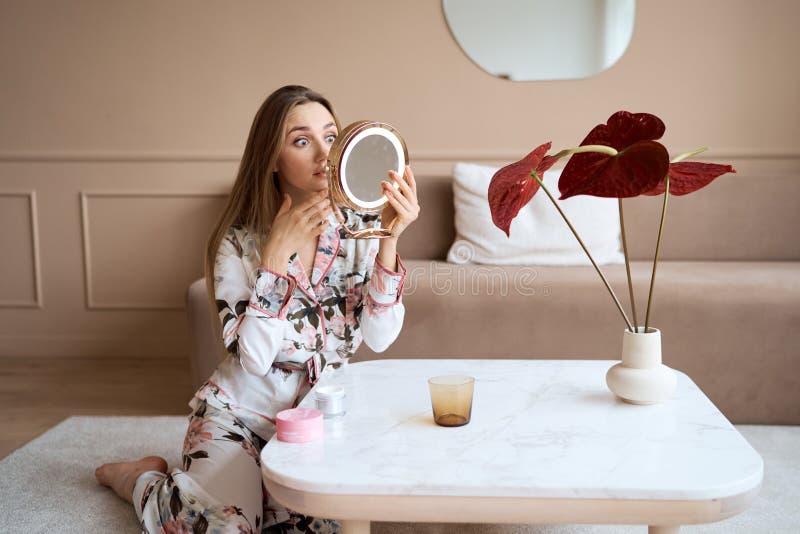 Mujer atractiva en pijama aplicar crema facial. atractiva joven en pijama aplicando crema hidratante en la cara fotos de archivo