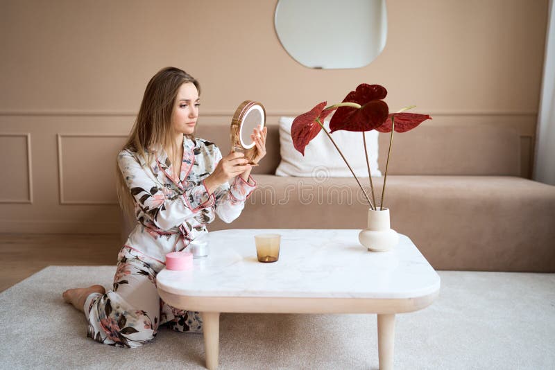 Mujer atractiva en pijama aplicar crema facial. atractiva joven en pijama aplicando crema hidratante en la cara imagen de archivo
