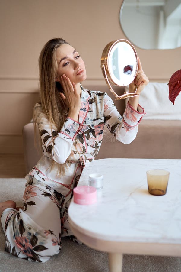 Mujer atractiva en pijama aplicar crema facial. atractiva joven en pijama aplicando crema hidratante en la cara fotografía de archivo