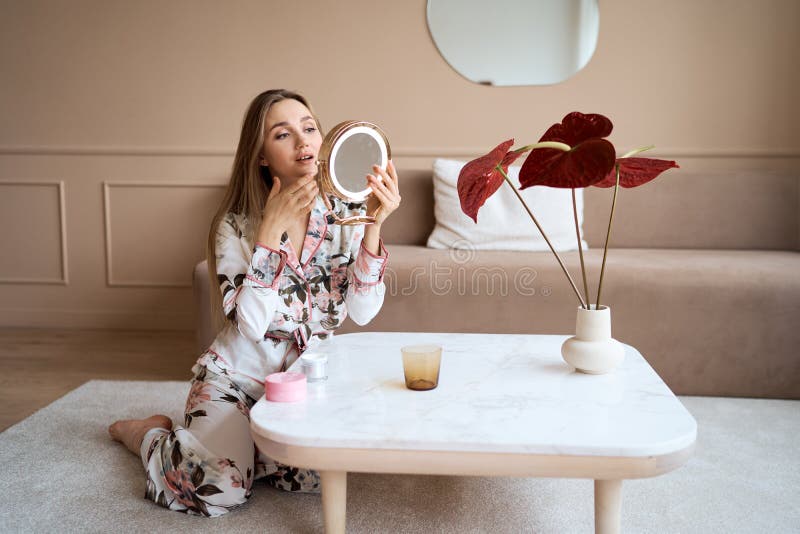Mujer atractiva en pijama aplicar crema facial. atractiva joven en pijama aplicando crema hidratante en la cara imagen de archivo libre de regalías