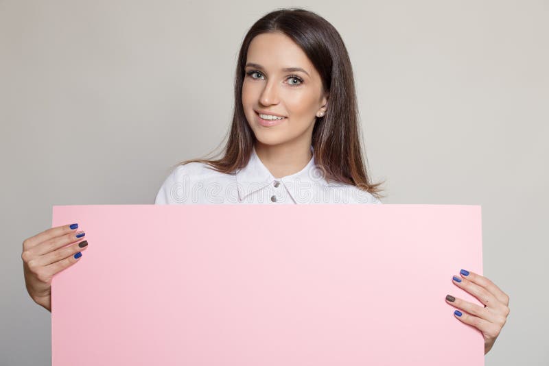 Mujer atractiva feliz que lleva a cabo el espacio en blanco rosado imágenes de archivo libres de regalías Mujer atractiva feliz que lleva a cabo el espacio en blanco rosado imágenes de archivo libres de regalías