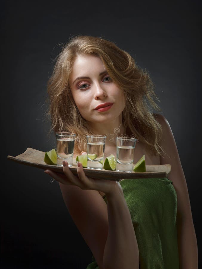 Mujer atractiva joven con las bebidas alcohólicas y las rebanadas de cal fotografía de archivo Mujer atractiva joven con las bebidas alcohólicas y las rebanadas de cal fotografía de archivo