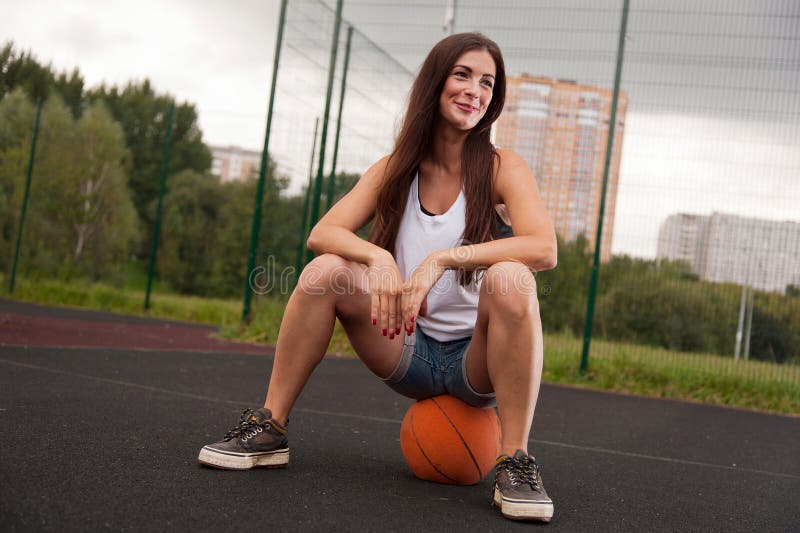 Mujer atractiva que se sienta en baloncesto imagenes de archivo Mujer atractiva que se sienta en baloncesto imagenes de archivo