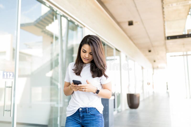 Mujer atractiva que usa el uso en Smartphone en el CEN que hace compras imagen de archivo Mujer atractiva que usa el uso en Smartphone en el CEN que hace compras imagen de archivo