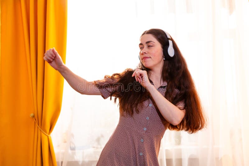 Mujer bailando en un tranquilo ambiente familiar perdido en el sonido y la emoción. Mid shot foto de archivo