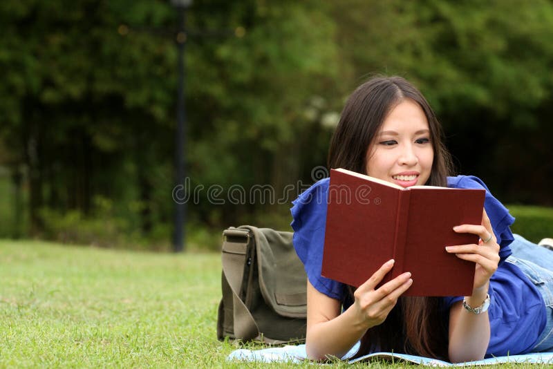 Mujer bastante joven que lee un libro en el parque fotografía de archivo libre de regalías Mujer bastante joven que lee un libro en el parque fotografía de archivo libre de regalías