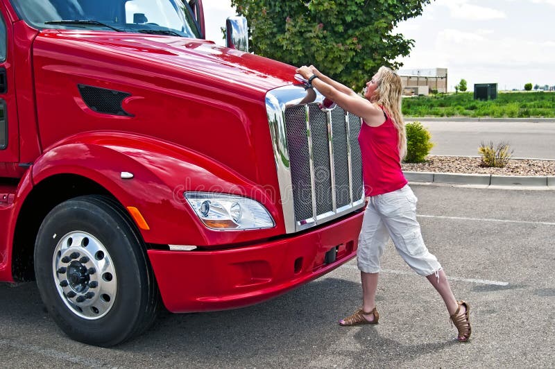 Mujer bastante rubia que abre un capo motor del carro. foto de archivo