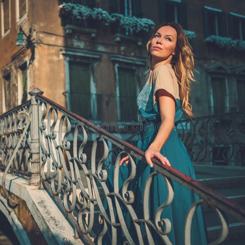 Mujer bien vestida hermosa que presenta en un puente sobre el canal en Venecia imagen de archivo Mujer bien vestida hermosa que presenta en un puente sobre el canal en Venecia imagen de archivo