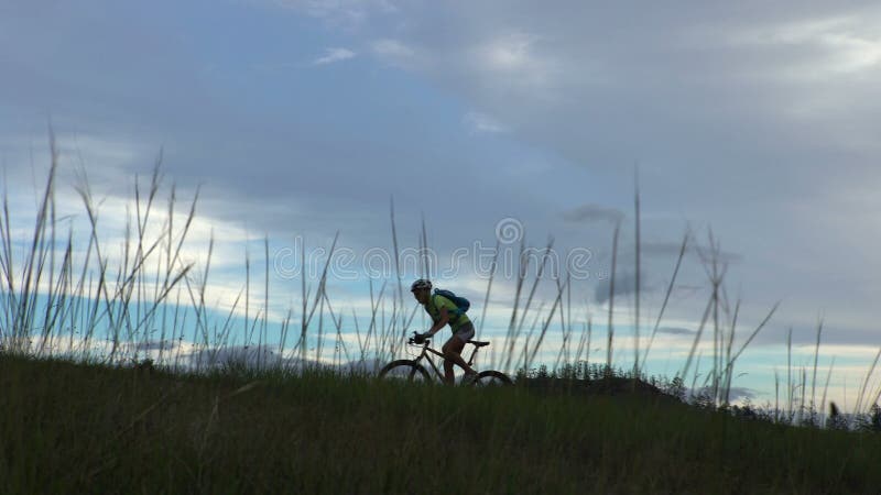 Mujer Biking que completa un ciclo en prado verde