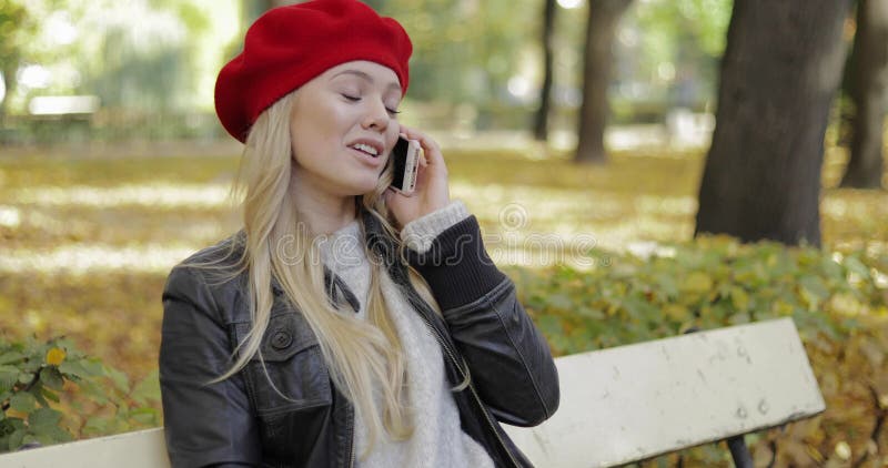 Mujer bonita en la boina que habla en el teléfono