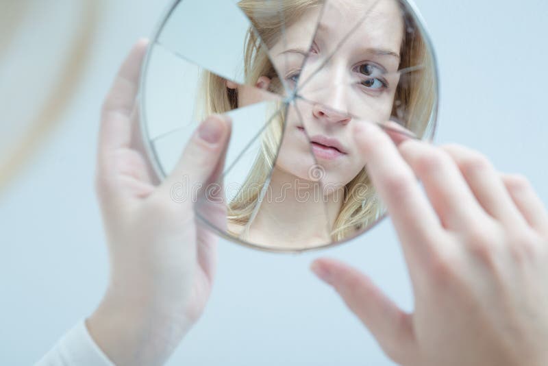 Insecure pretty young woman holding broken mirror. Insecure pretty young woman holding broken mirror