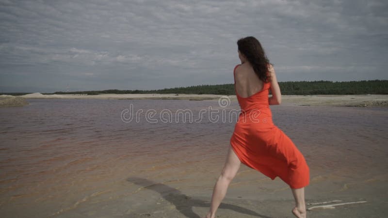 Mujer bonita que baila cerca del agua