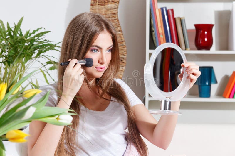 Mujer bonita que pone maquillaje foto de archivo