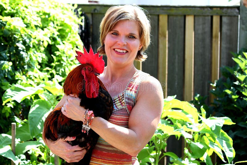Mujer bonita que sostiene un gallo fotos de archivo libres de regalías Mujer bonita que sostiene un gallo fotos de archivo libres de regalías