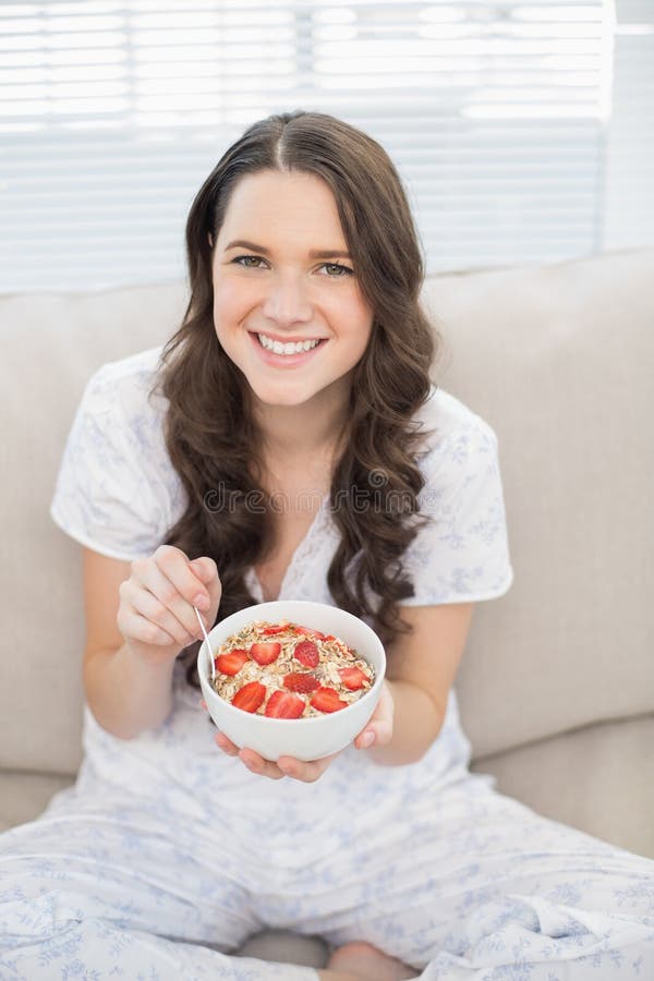 Mujer bonita sonriente en pijamas que come el cereal con sabor a fruta fotos de archivo libres de regalías Mujer bonita sonriente en pijamas que come el cereal con sabor a fruta fotos de archivo libres de regalías