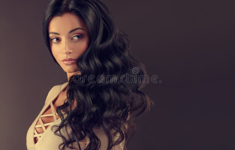 Mujer cabelluda negra joven con el pelo voluminoso, brillante y ondulado foto de archivo libre de regalías Mujer cabelluda negra joven con el pelo voluminoso, brillante y ondulado foto de archivo libre de regalías
