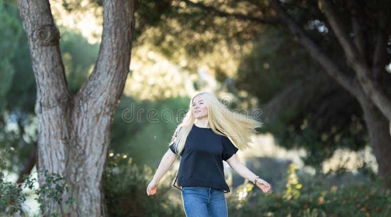 Mujer caminando entre árboles en el parque fotos de archivo