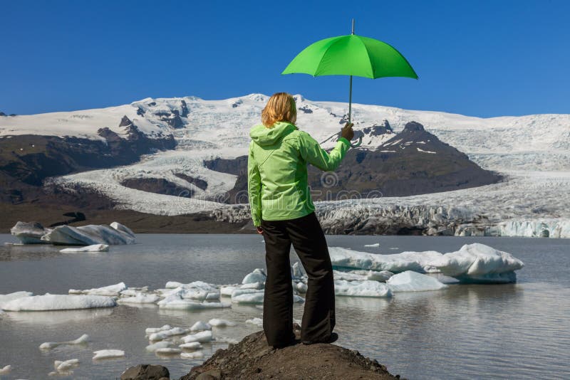 Mujer caminante con paraguas verde mirando a un glaciar derritiéndose en Islandia foto de archivo Mujer caminante con paraguas verde mirando a un glaciar derritiéndose en Islandia foto de archivo