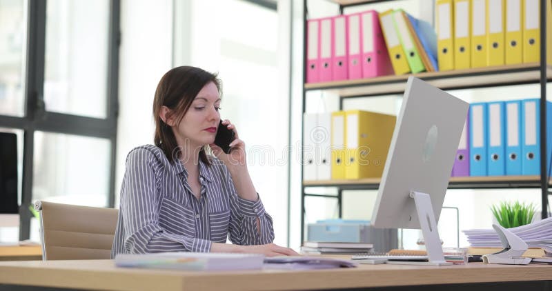 Mujer cansada usa smartphone en su oficina durante la jornada laboral almacen de video