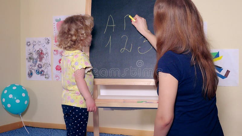 Mujer cariñosa de la madre y sus letras y números de la escritura de la muchacha de la hija