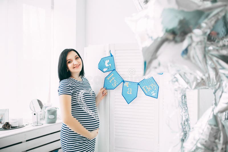 Mujer caucásica embarazada hermosa feliz con el vientre grande en vestido en la habitación del niño con los globos, parrents futu imágenes de archivo libres de regalías Mujer caucásica embarazada hermosa feliz con el vientre grande en vestido en la habitación del niño con los globos, parrents futu imágenes de archivo libres de regalías
