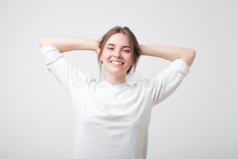Mujer caucásica joven despreocupada feliz en la camiseta blanca con una mueca linda que presenta con sus manos sobre su cabeza imágenes de archivo libres de regalías Mujer caucásica joven despreocupada feliz en la camiseta blanca con una mueca linda que presenta con sus manos sobre su cabeza imágenes de archivo libres de regalías