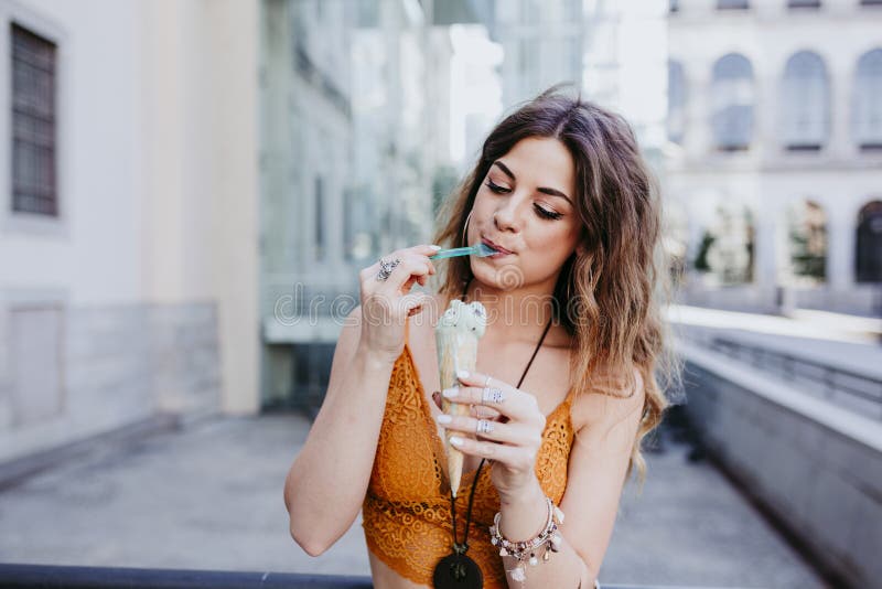 Mujer caucásica joven hermosa que come el helado de la menta en la calle de la ciudad en un día soleado Sonrisa feliz de la cara imágenes de archivo libres de regalías Mujer caucásica joven hermosa que come el helado de la menta en la calle de la ciudad en un día soleado Sonrisa feliz de la cara imágenes de archivo libres de regalías