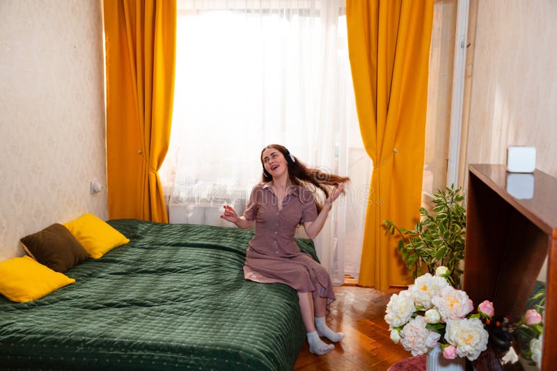 Mujer caucásica relajada cantando en la cama balanceándose al ritmo de su canción favorita. Imagen de pantalla ancha fotos de archivo